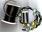 roll of black, hexagonal hawk's eye beads, and black seed beads
